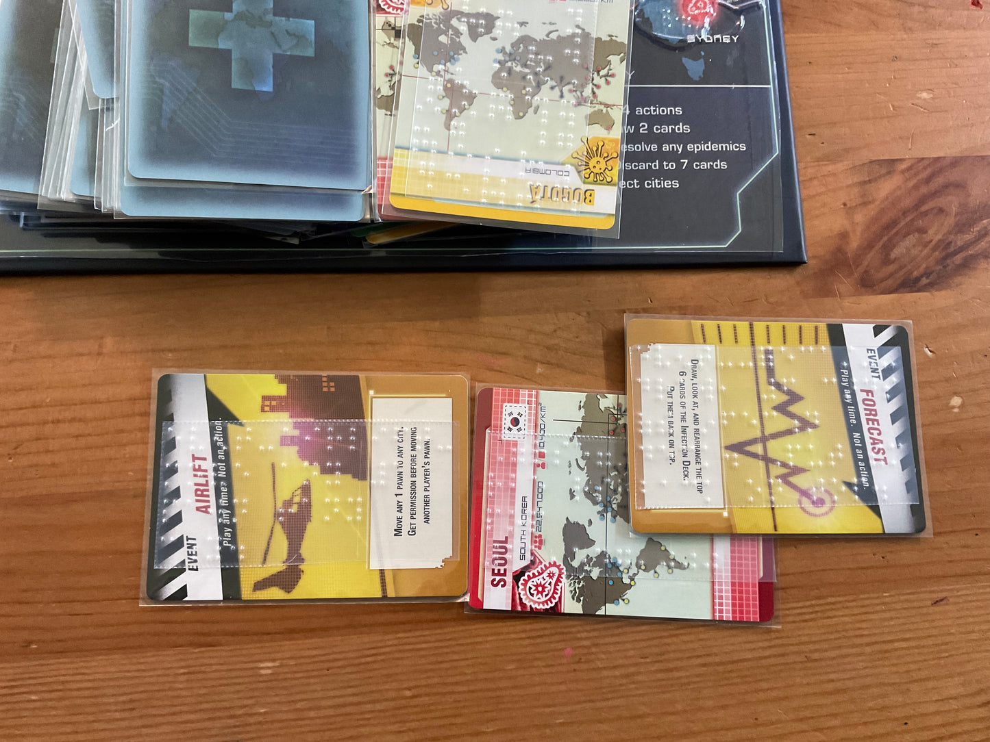 Player cards are shown. 2 event cards have transparent braille on them