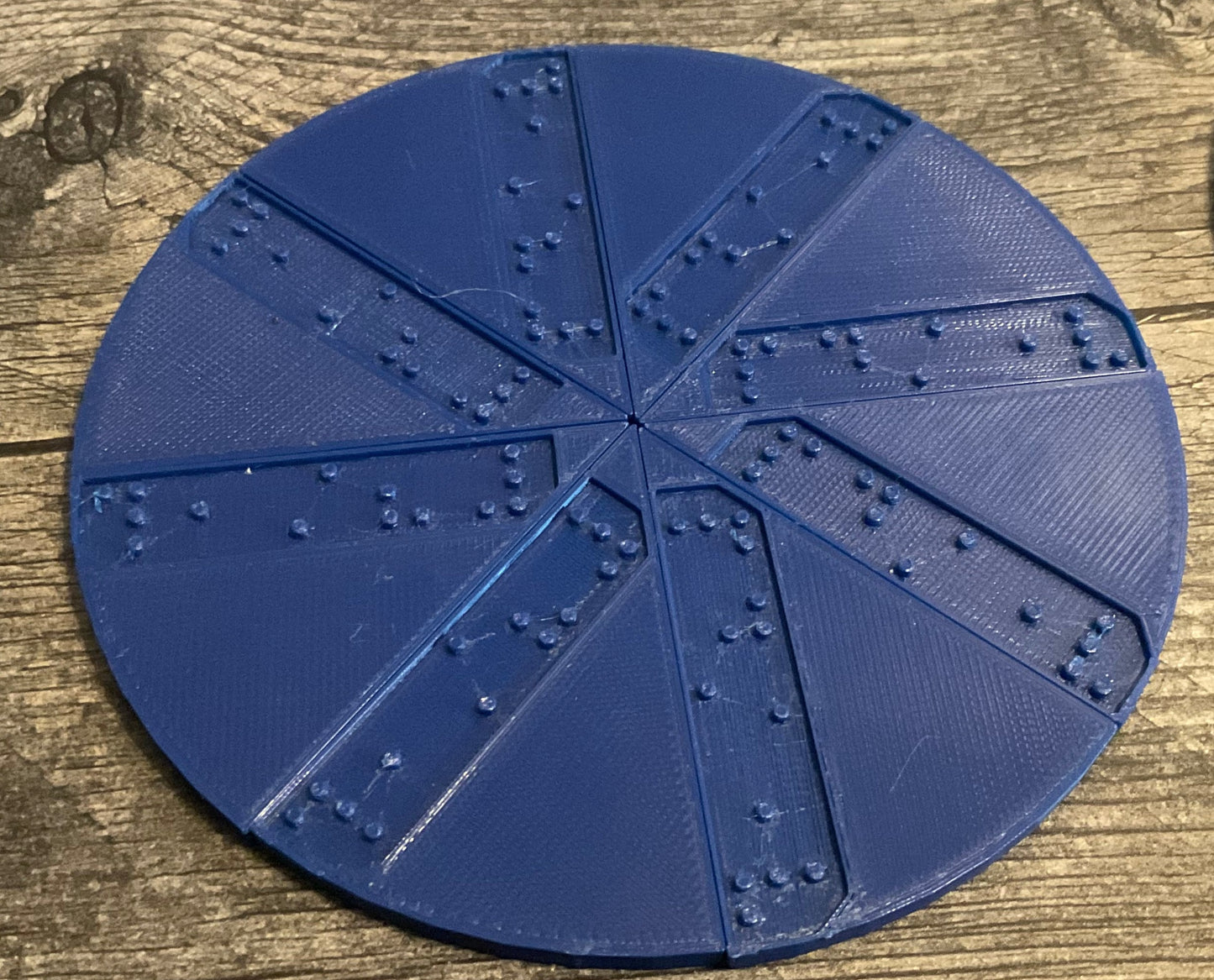 A circle cut in to 8 different pieces. Each piece has an indented section that says 1/8 in braille.