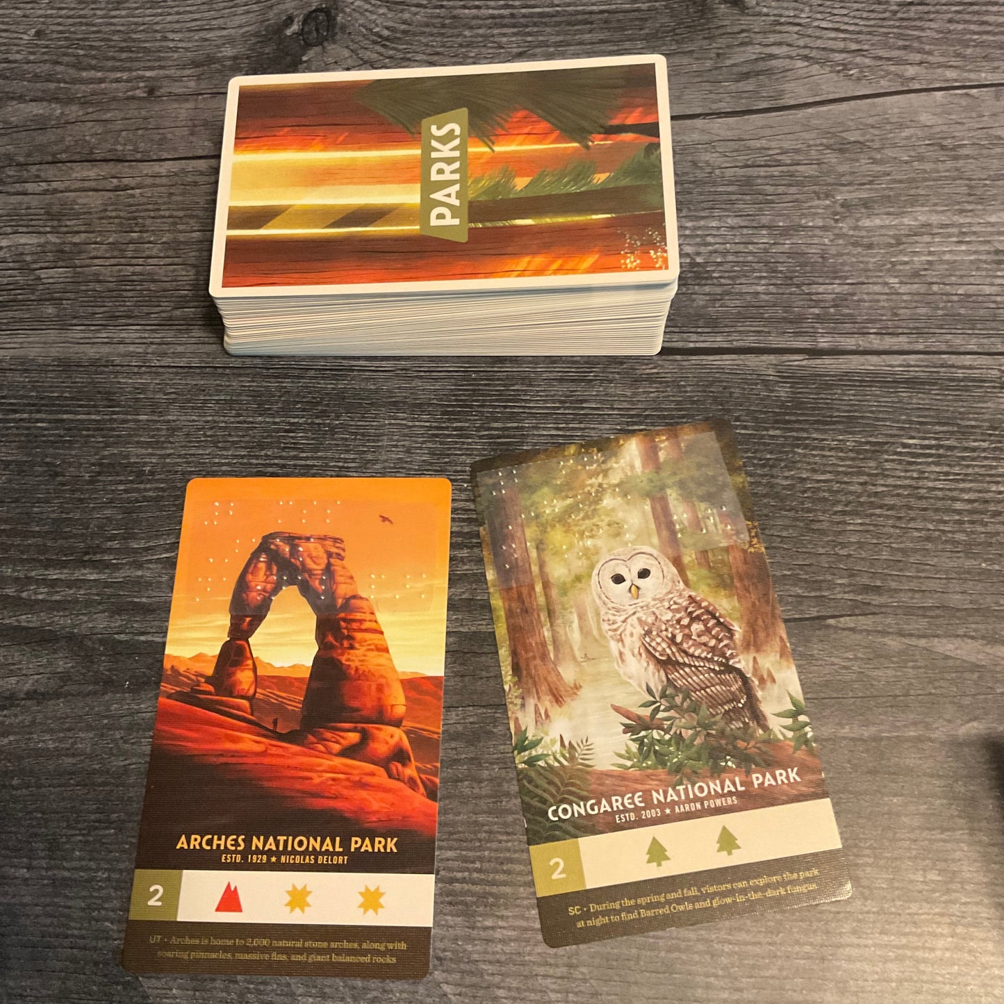 The parks deck with 2 parks face up in front of it. the name of both parks are in braille along with the type of landscape
