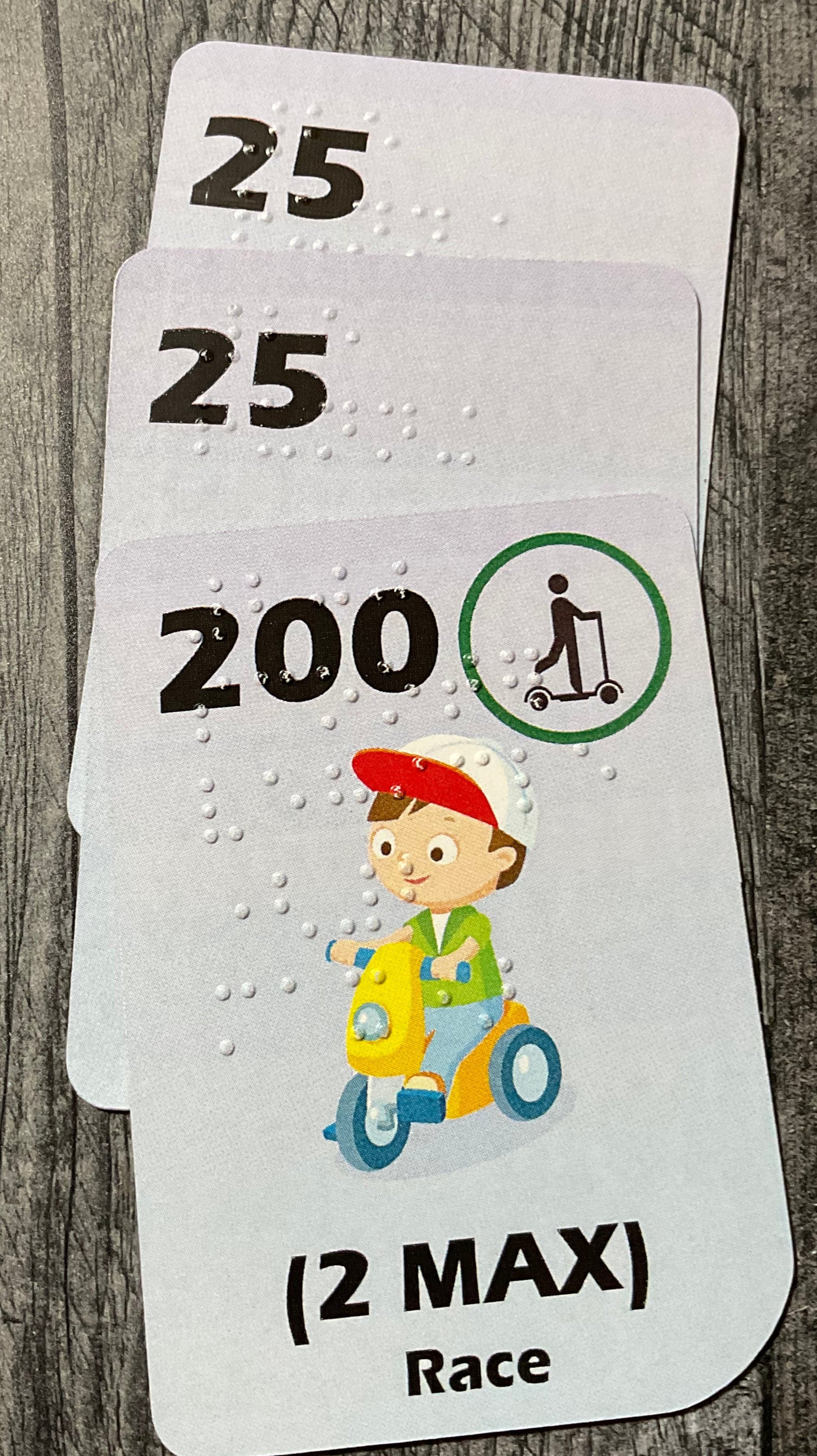 A close up of a stack of Race cards. A scooter card can be seen  on the top of the stack.