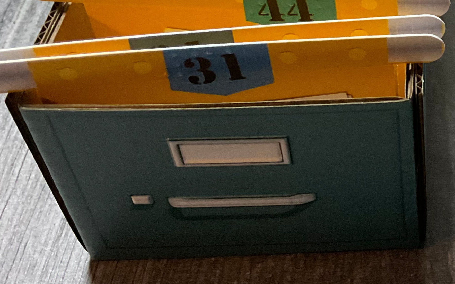 A close up shot of the folders in a filing cabinets. The cabinet itself is tactile with a 'handle' and a 'label'