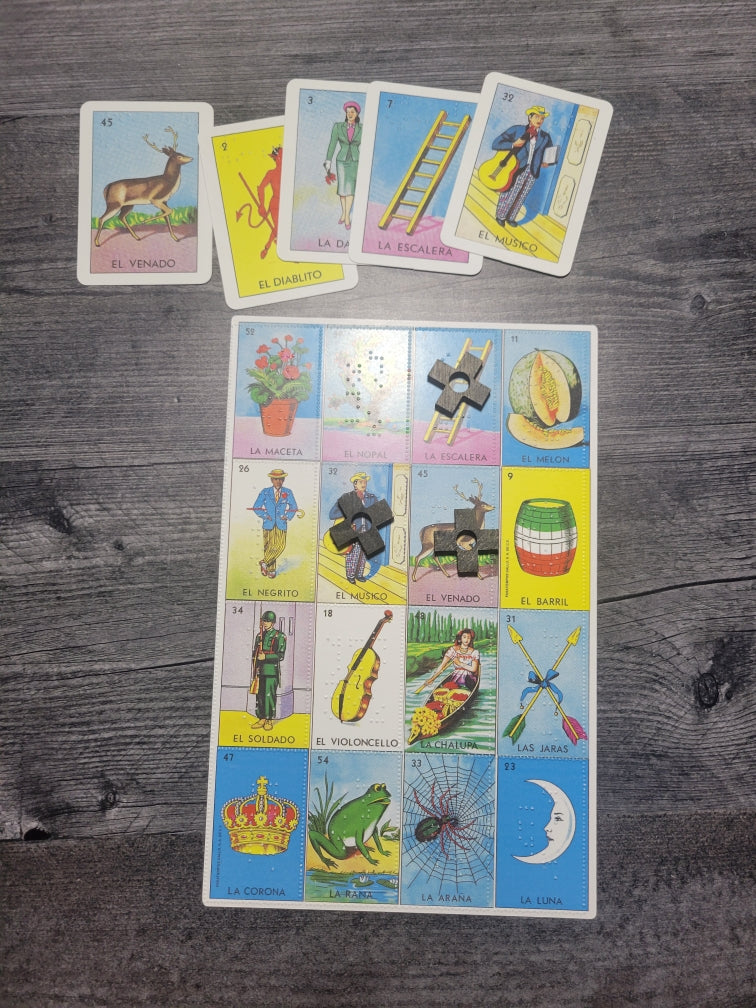 The Loteria board with some tokens on it and 5 call cards laid out above it.