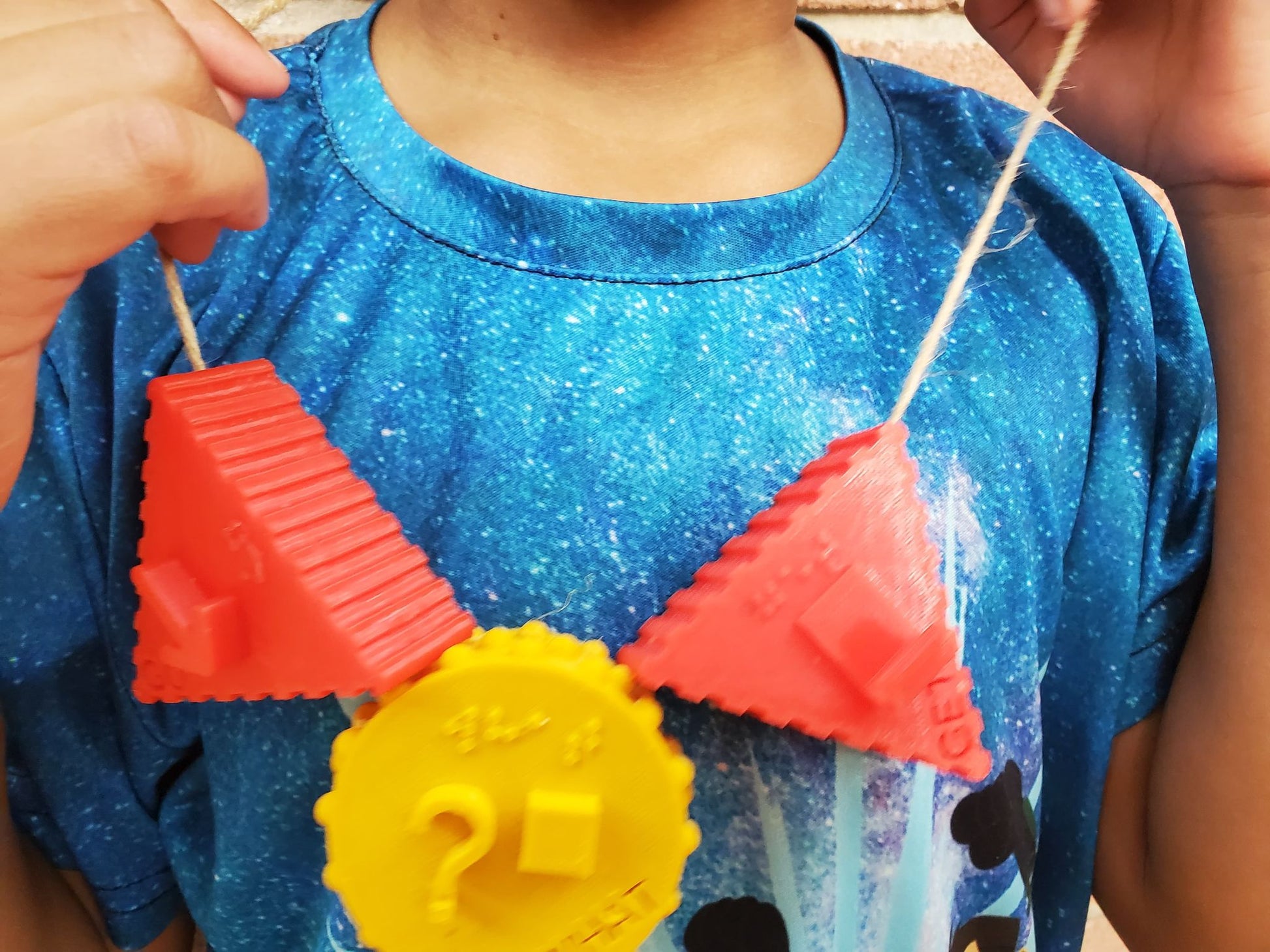 Close up on necklace that child is wearing with 3 symbols on it