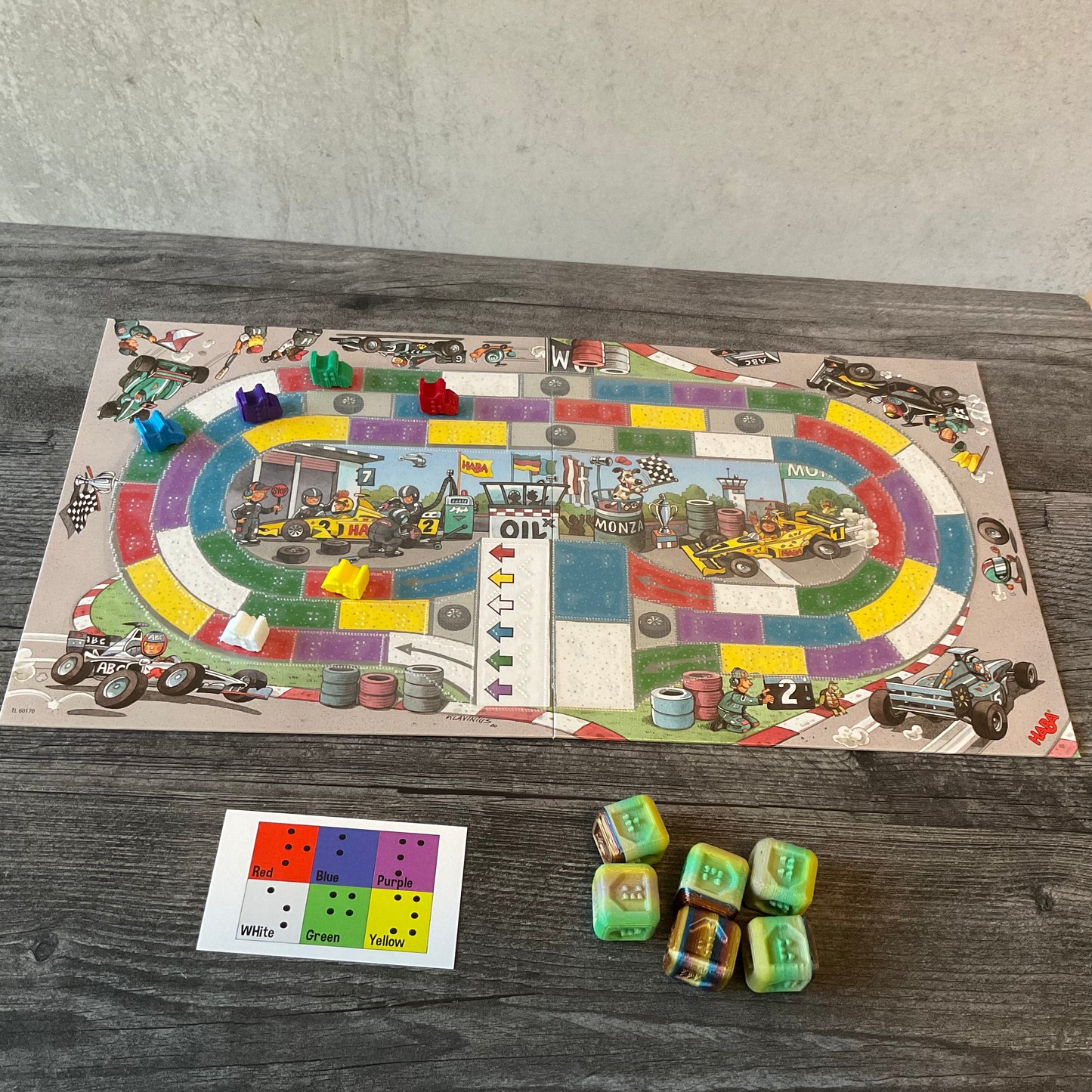 Wide shot of the board with the 3d printed cars, the board overlay, the print dice reference card and the 3d printed replacement dice.