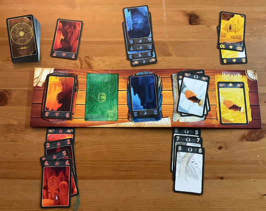 A picture of the game and the board laid out. Braille stickers are on all of the cards and the board. The board is two sided and the 5 expedition side is shown.