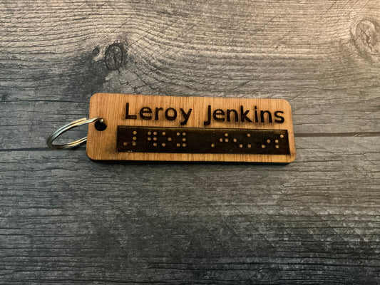 A cane tag with the words "Leroy Jenkins" engraved into it in both print and braille.