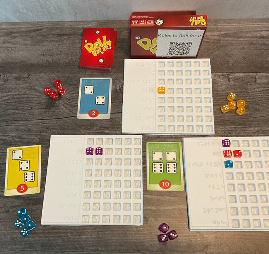 The game is shown setup(red version). There are trays next to the cards to sort who's dice are who's. The cards all have transparent braille on them indicated the needed dice and their point value