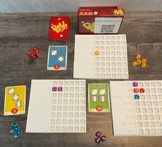 The game is shown setup(red version). There are trays next to the cards to sort who's dice are who's. The cards all have transparent braille on them indicated the needed dice and their point value