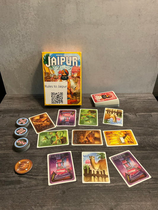 The game Jaipur laid out with a market in the middle between two players. The different favor tokens are shown to the left, with braille on both sides of the tokens