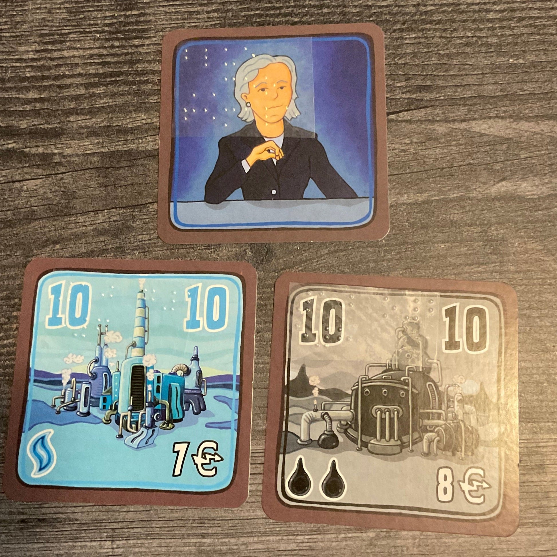 A blue CEO card and 2 factory cards, one for natural gas and one for oil. The cost, the amount of storage and rank are shown on the cards in braille