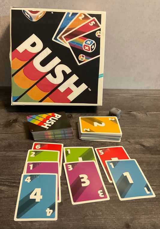 The game push. The cards with their numbers and colors are arranged in rows as one would do in the game. The 3d printed die can be seen in the background