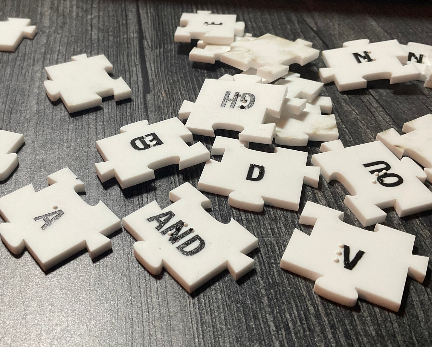 A close up on the tiles showing the braille and the large print on them. Each tile fits together with puzzle piece like tabs so that they will not move apart.