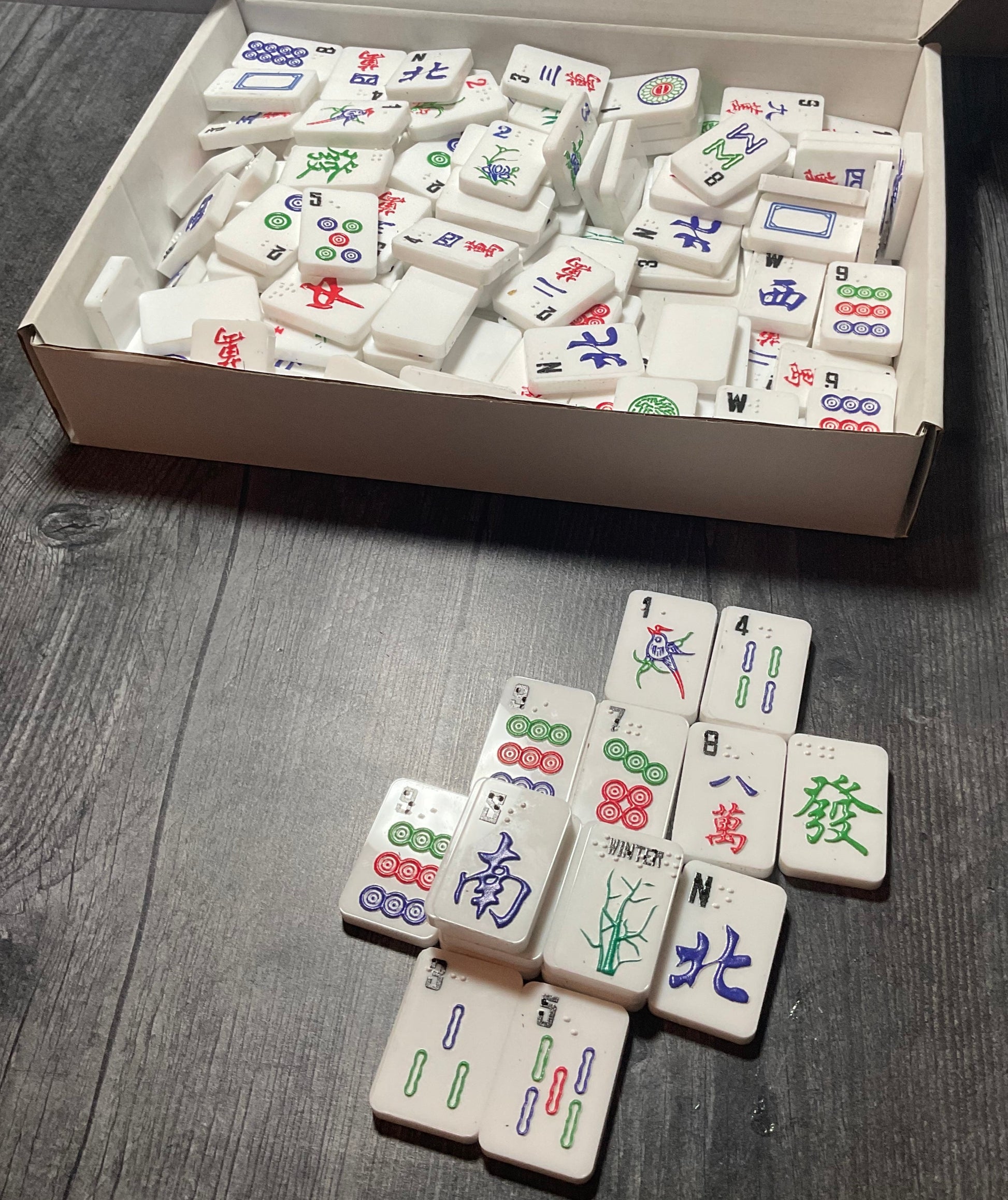 A shot of the box showing all of the included tiles. Some of the tiles are stacked in front of the box.