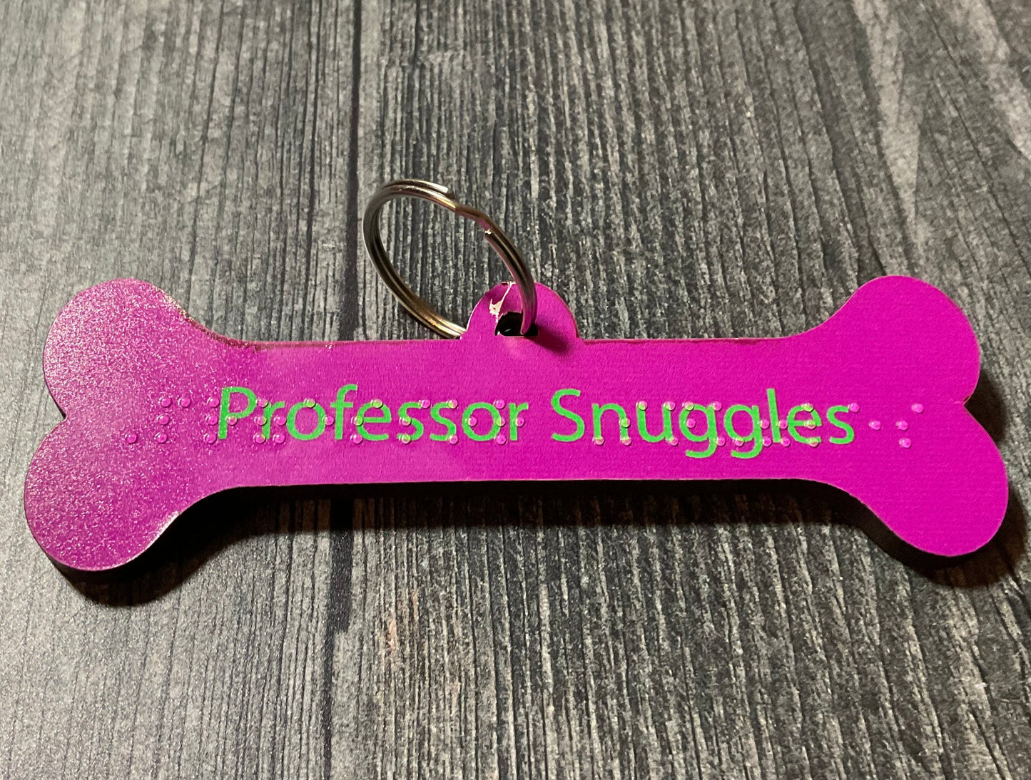 Close up on the long Professor Snuggles dog tag. It is purple.