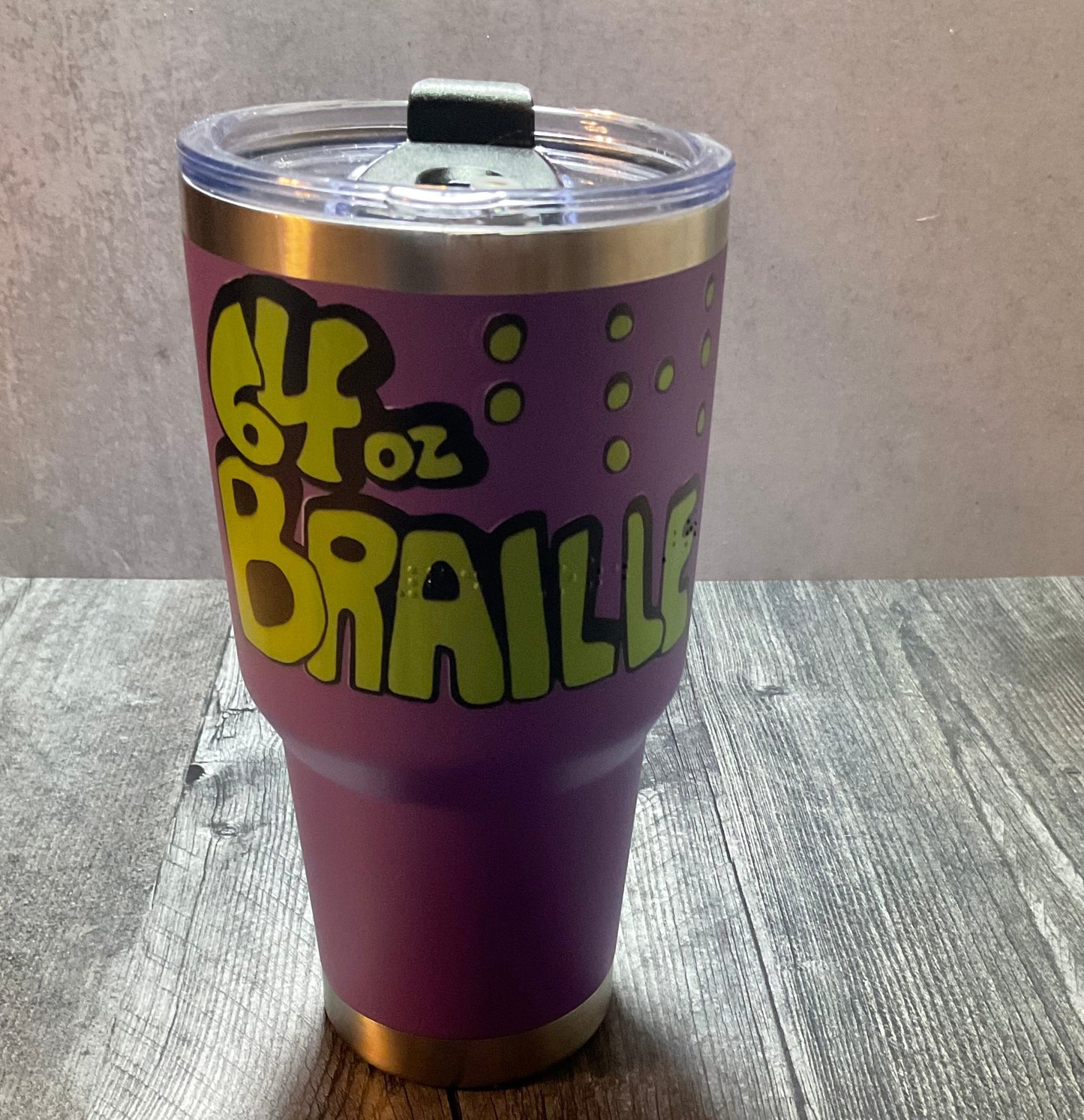 Purple 32 Oz. tumbler with tactile image and "64 Oz. Games" in braille printed on it.