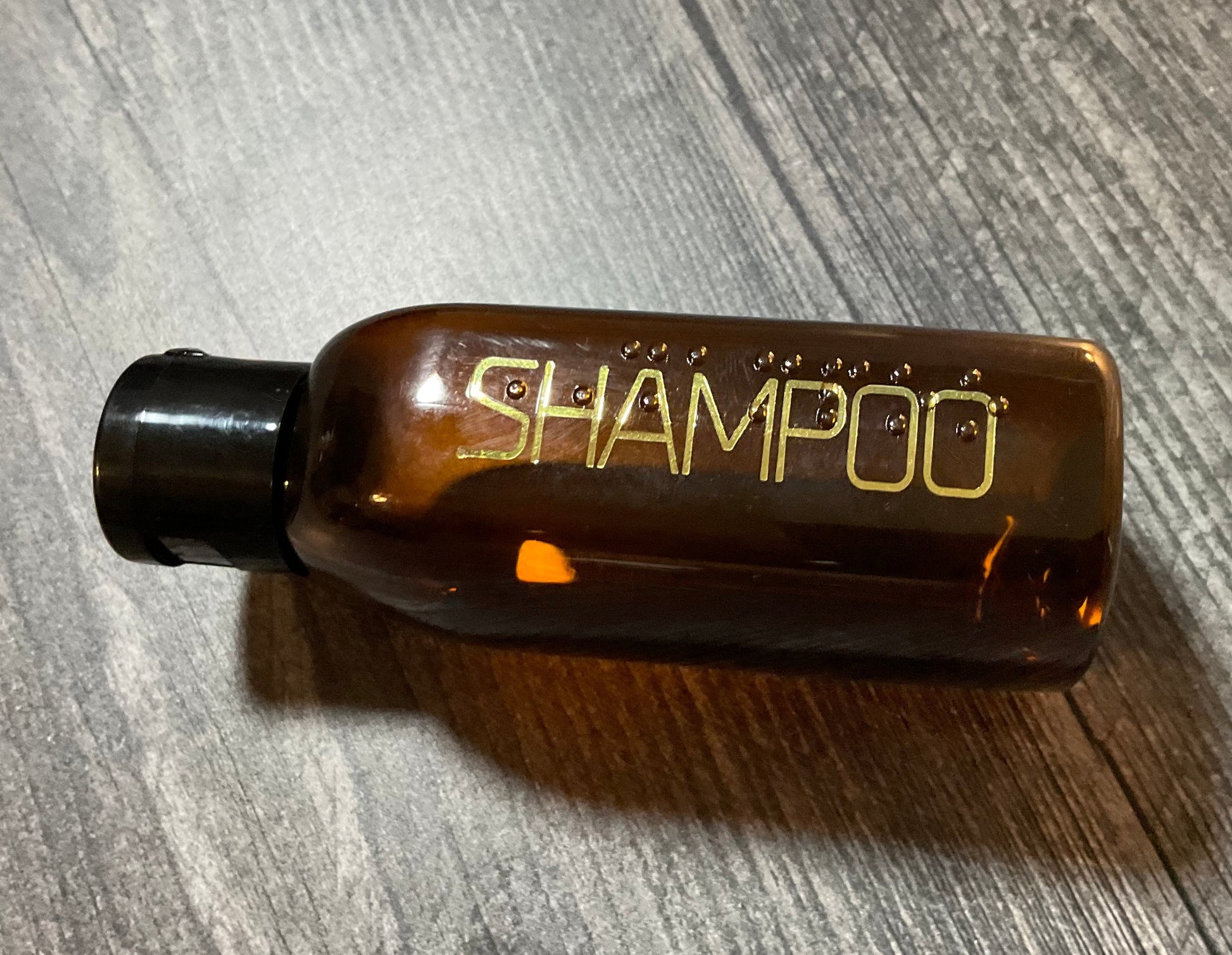 Close up on the shampoo bottle with print and braille on it.