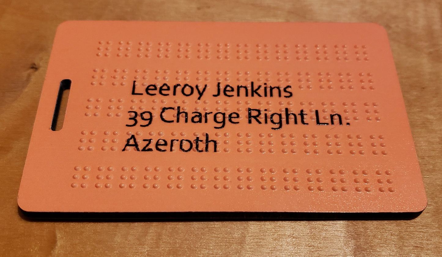 Orange luggage tag showing our "microbraille" that adds a few more lines. The address is printed in plain ink on top of the braille.