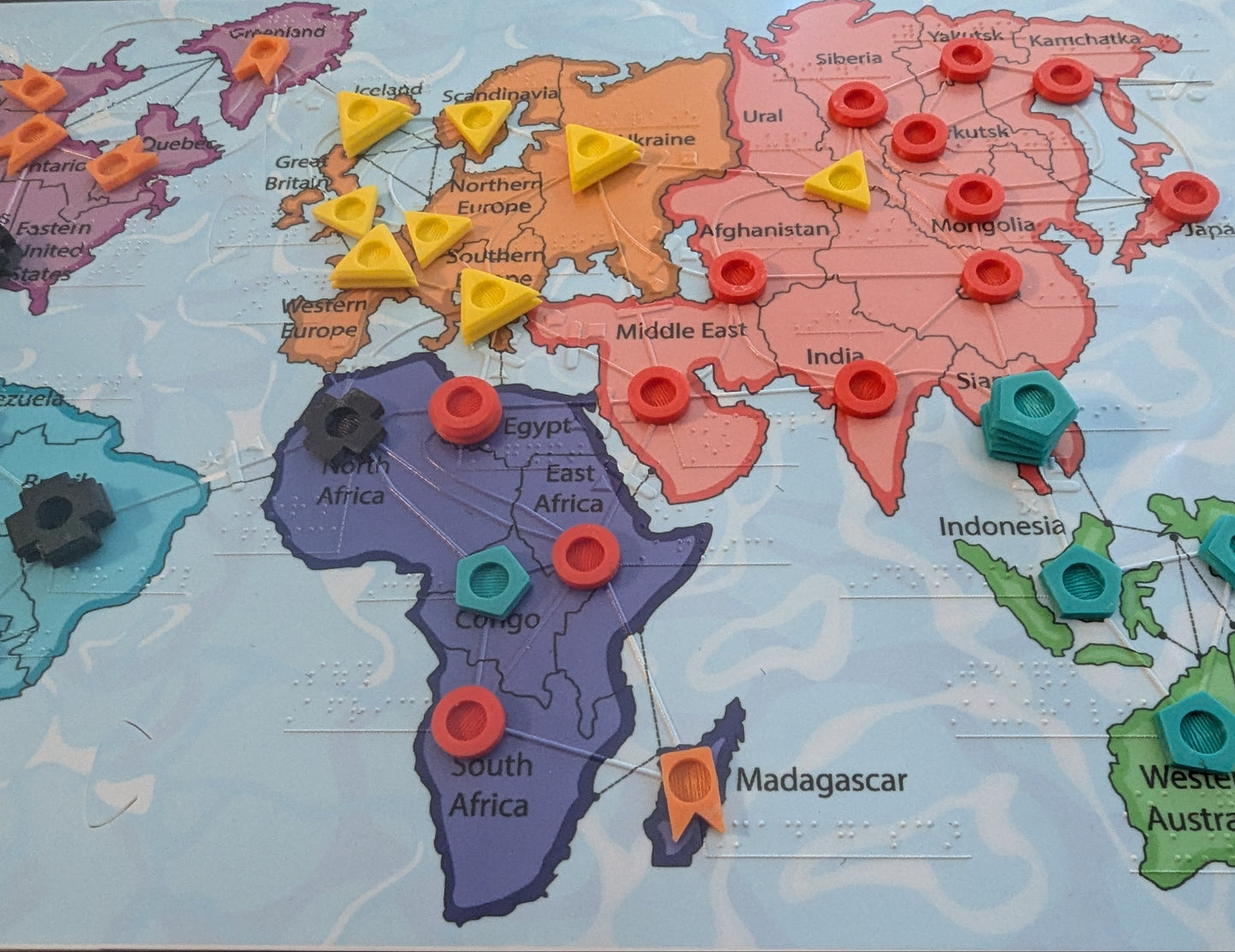 World map with colorful tactile pins on each of countries. Some of them are stacked higher than others and some of the pins are different shapes.