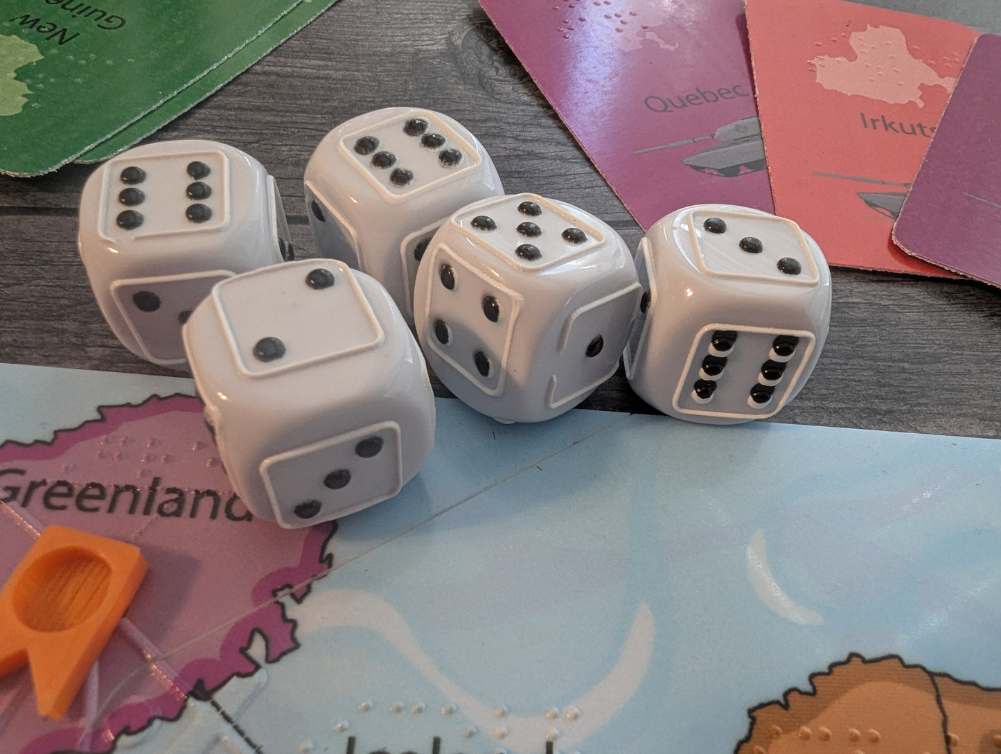 Five dice on a board game. The dice are all tactile.