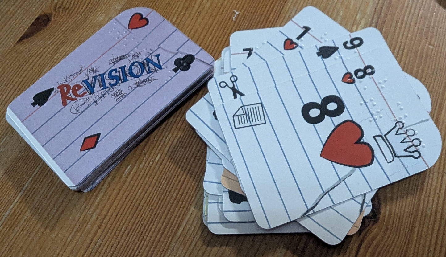 A deck of playing cards styled like lined notebook pages with black ink markings and red heart details. Each card has both large print, icons and braille on them.